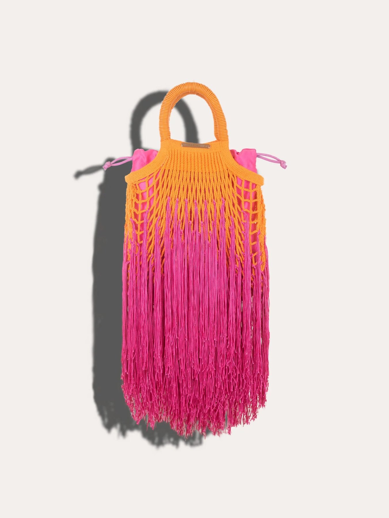 A hand-tied fringe net bag in orange and fuchsia